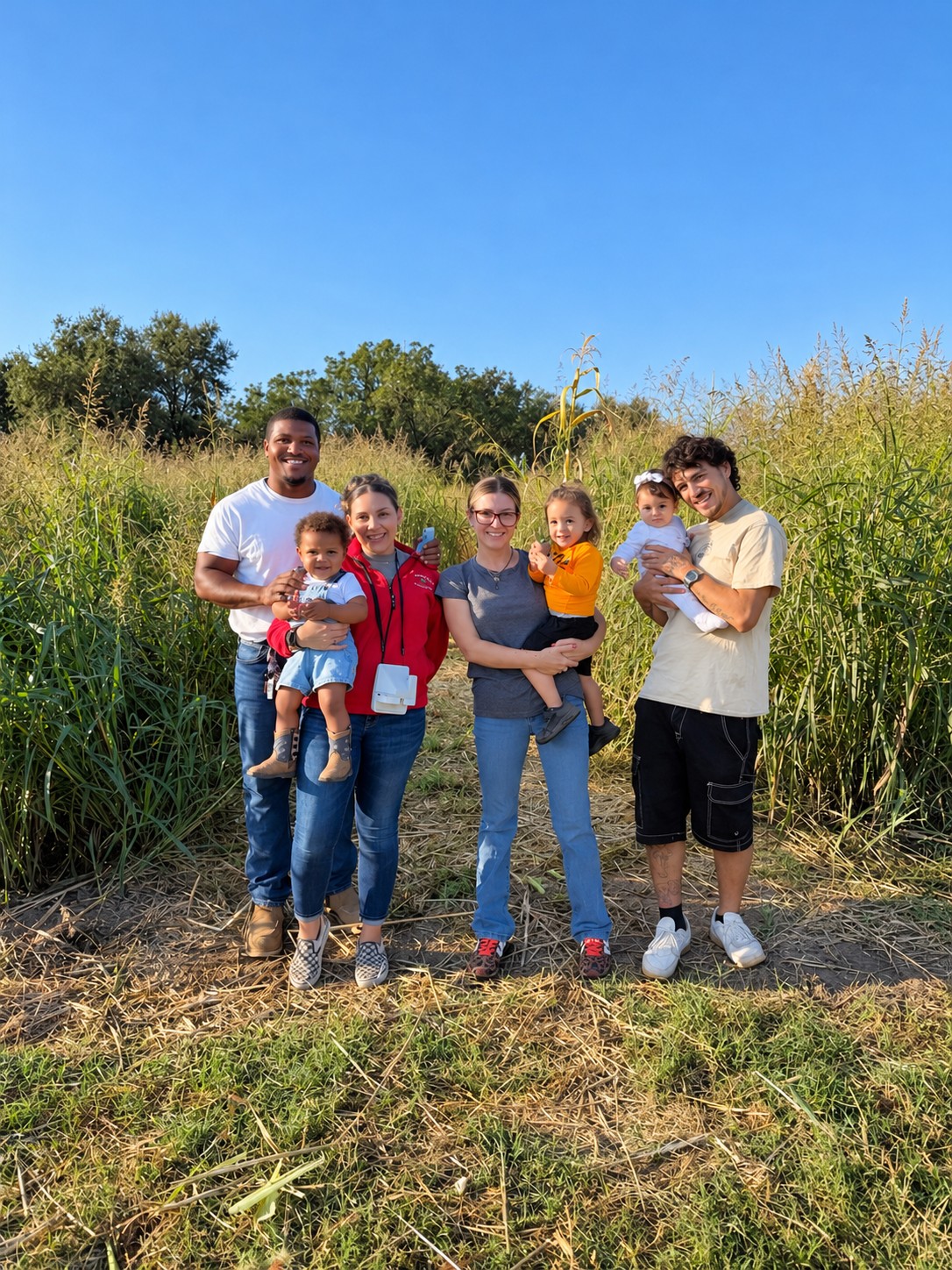 Adults and children posing together at the entrance to the farm maze