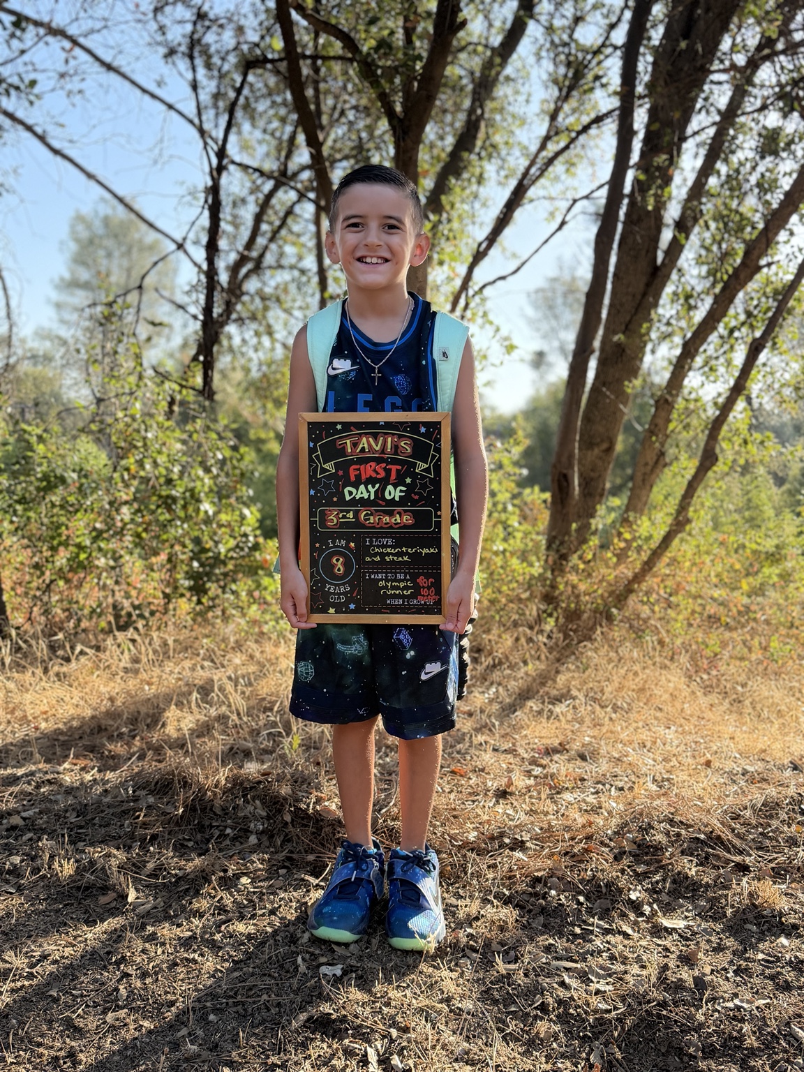 Tavi smiling with his first-day-of-school sign